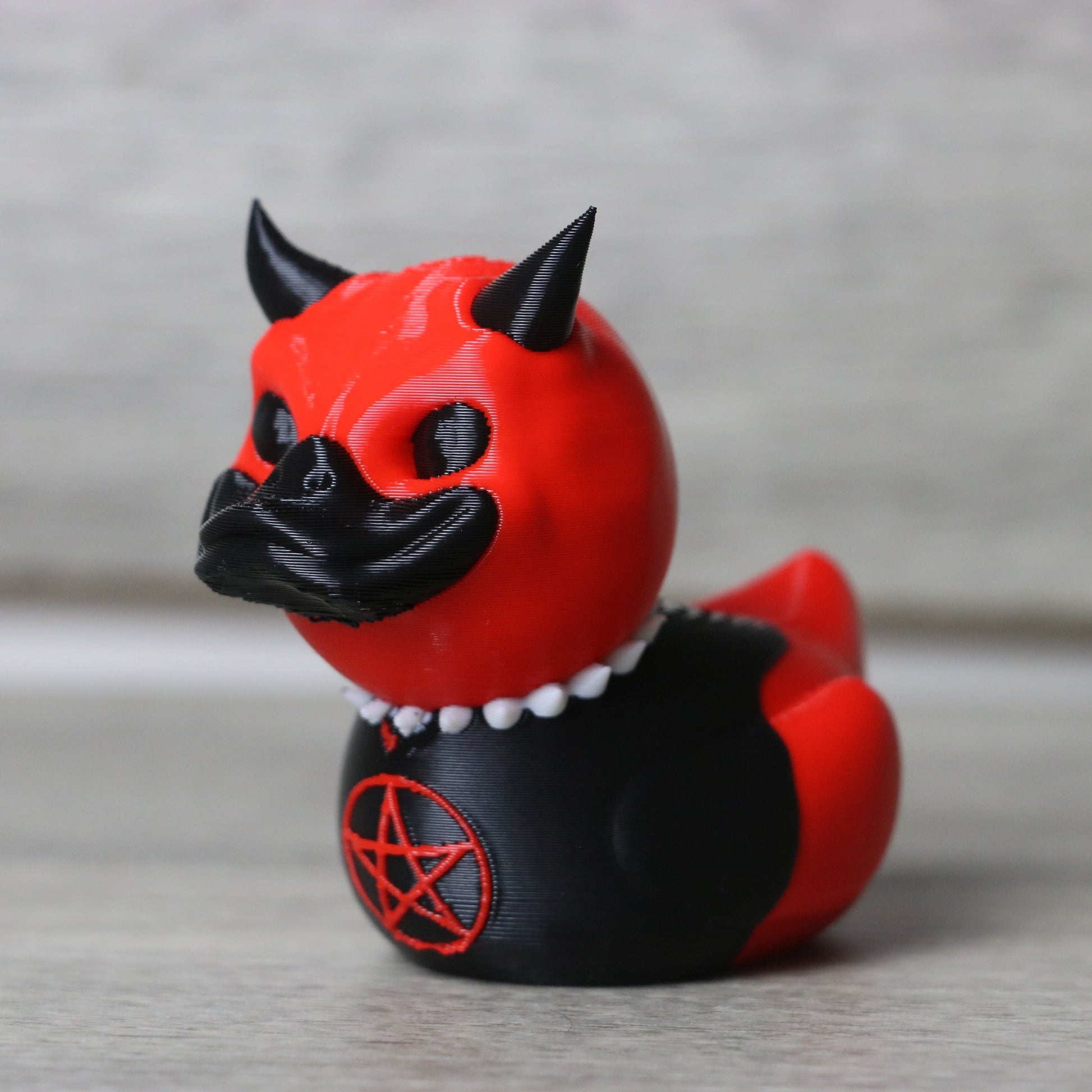 Red and black figurine with horns on a gray background