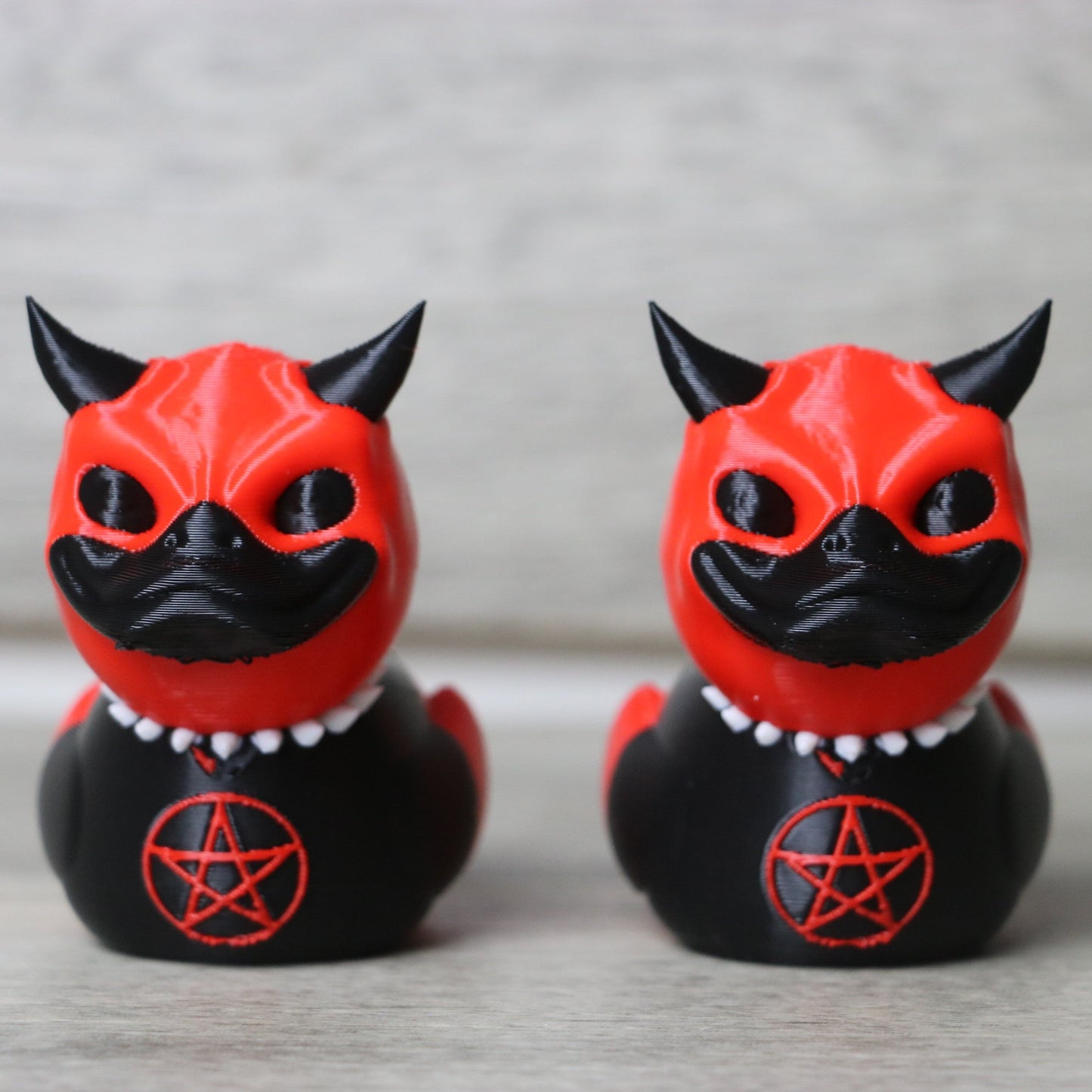 Two red and black cat figurines with pentacle symbols on a neutral background